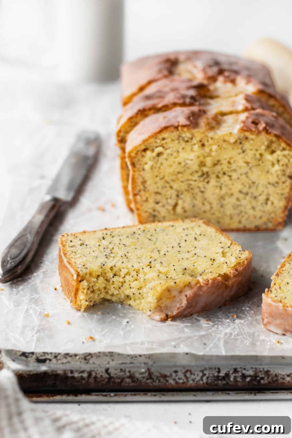 A bitten slice of gluten free lemon bread with the loaf in the background.