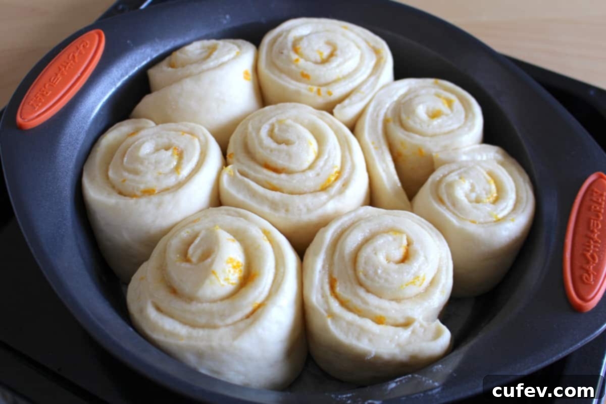 A round baking pan filled with lemon rolls that have doubled in size after proofing, indicating they are ready for baking.