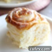 A square hero shot of a fluffy lemon roll on a white plate.