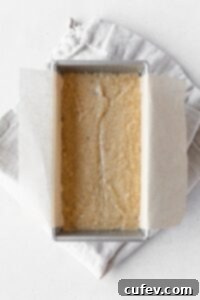 Banana bread batter in a loaf tin on a folded linen napkin.