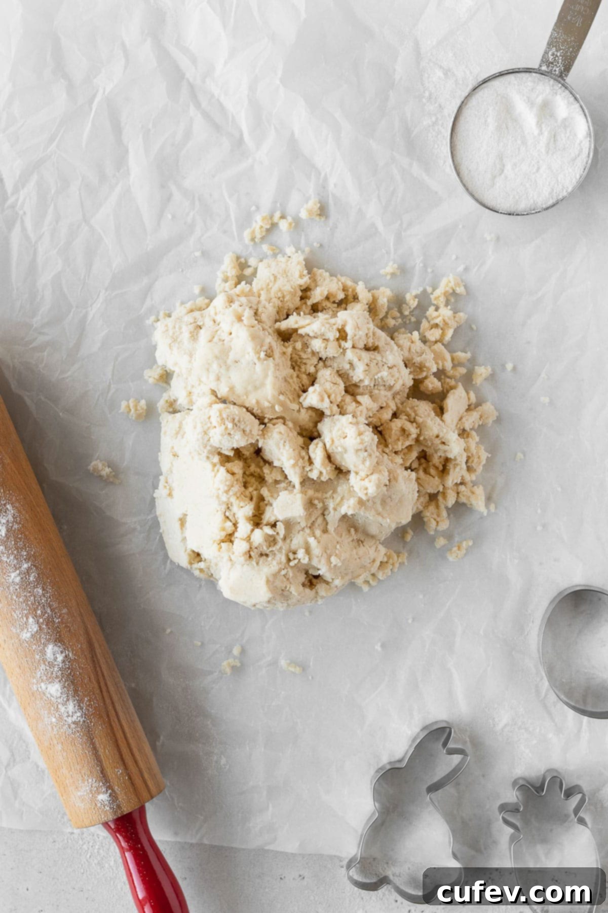 Cookie dough on parchment paper with some cookie cutters.