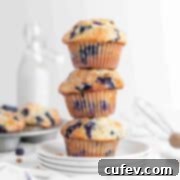 Bursting Blueberry Muffins 7 A stack of three blueberry muffins on white plates.