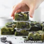 A hand reaching for a stack of matcha blondies