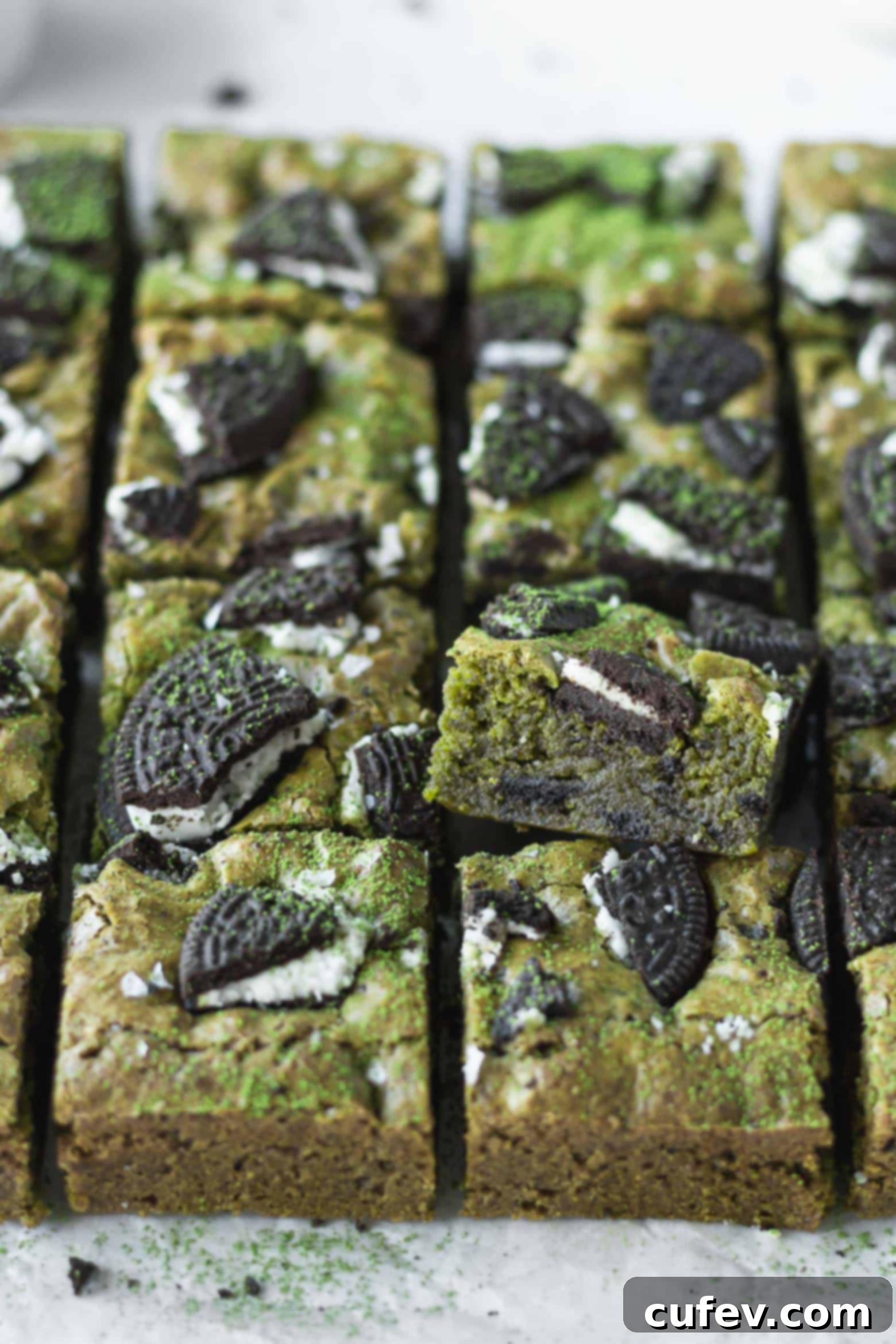 Close-up of freshly baked matcha blondies sliced into squares, highlighting their green color and Oreo bits.