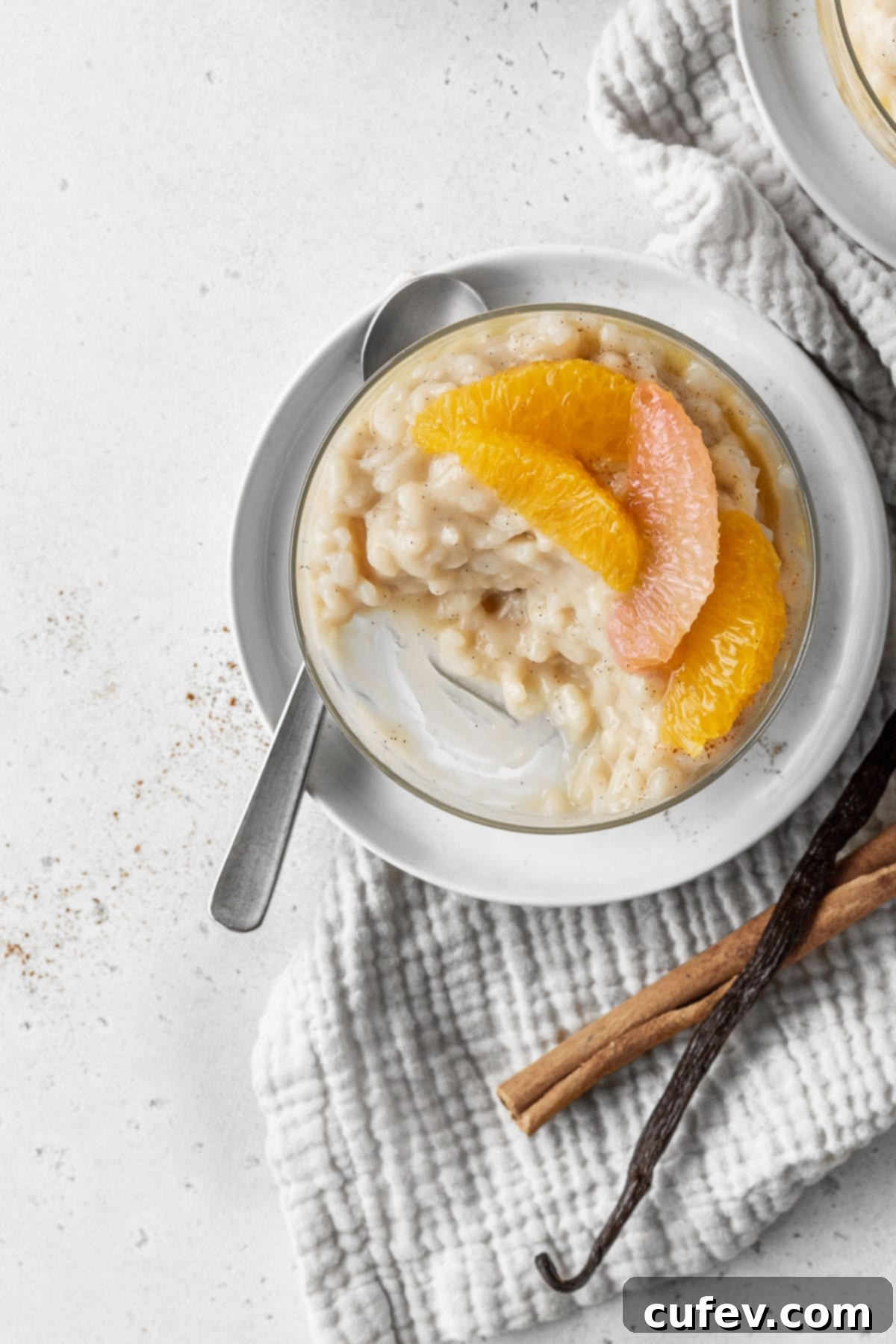 A half-eaten serving of vegan rice pudding in a glass, beautifully topped with fresh citrus segments from the compote, showing its inviting texture and vibrant garnish.