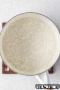 A pot of white rice simmering in water, preparing the base for creamy rice pudding.