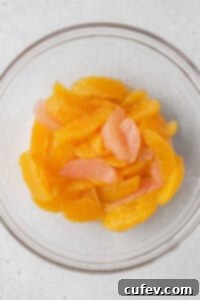 Freshly cut orange and grapefruit segments arranged beautifully in a clear glass bowl.