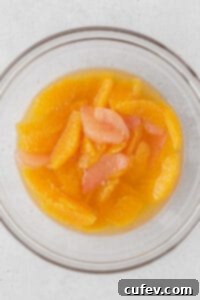 Vibrant citrus compote, featuring orange and grapefruit segments bathed in a spiced syrup, in a glass bowl.
