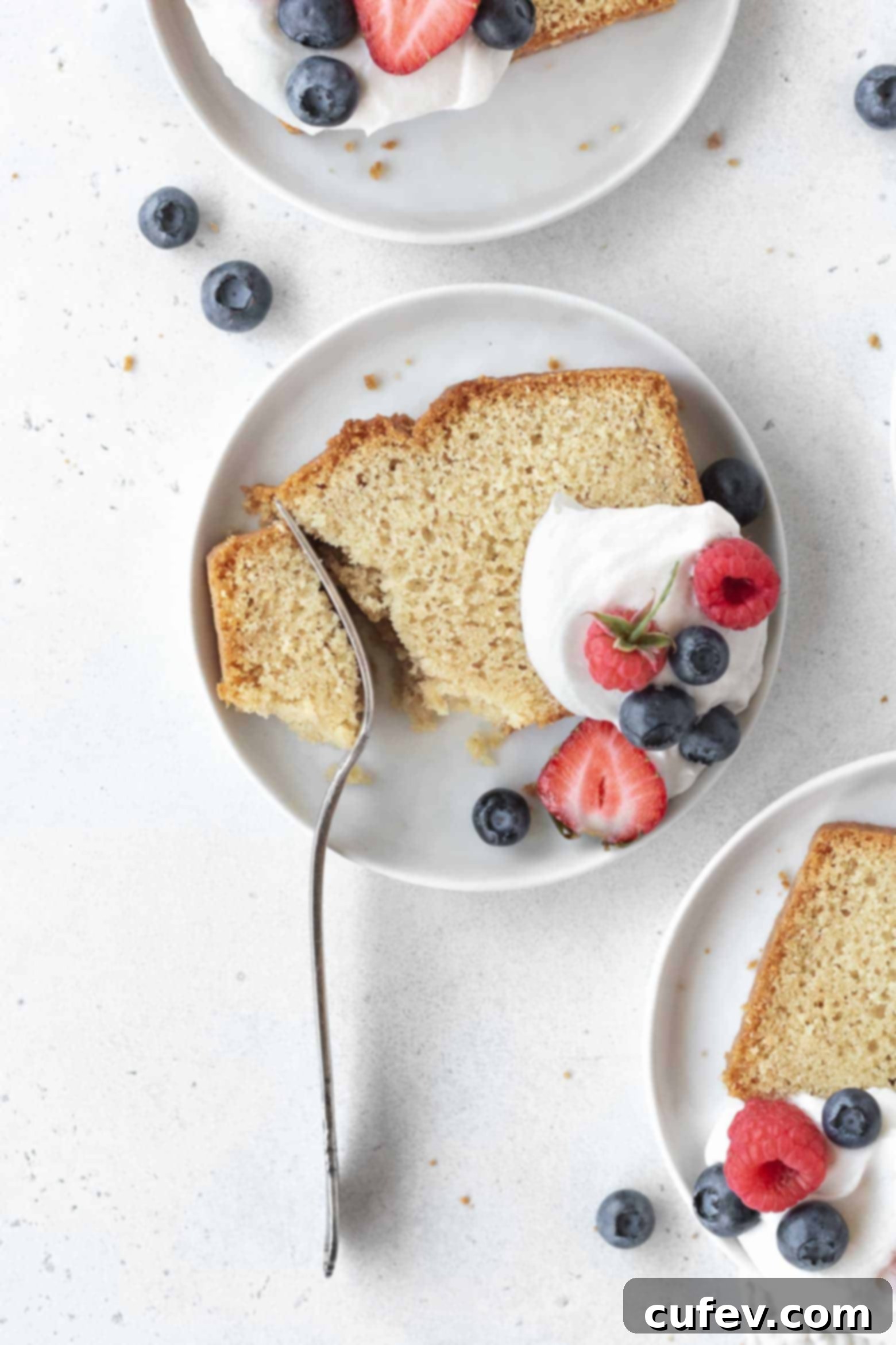 A fork gently cutting into a moist slice of gluten-free pound cake on a plate.