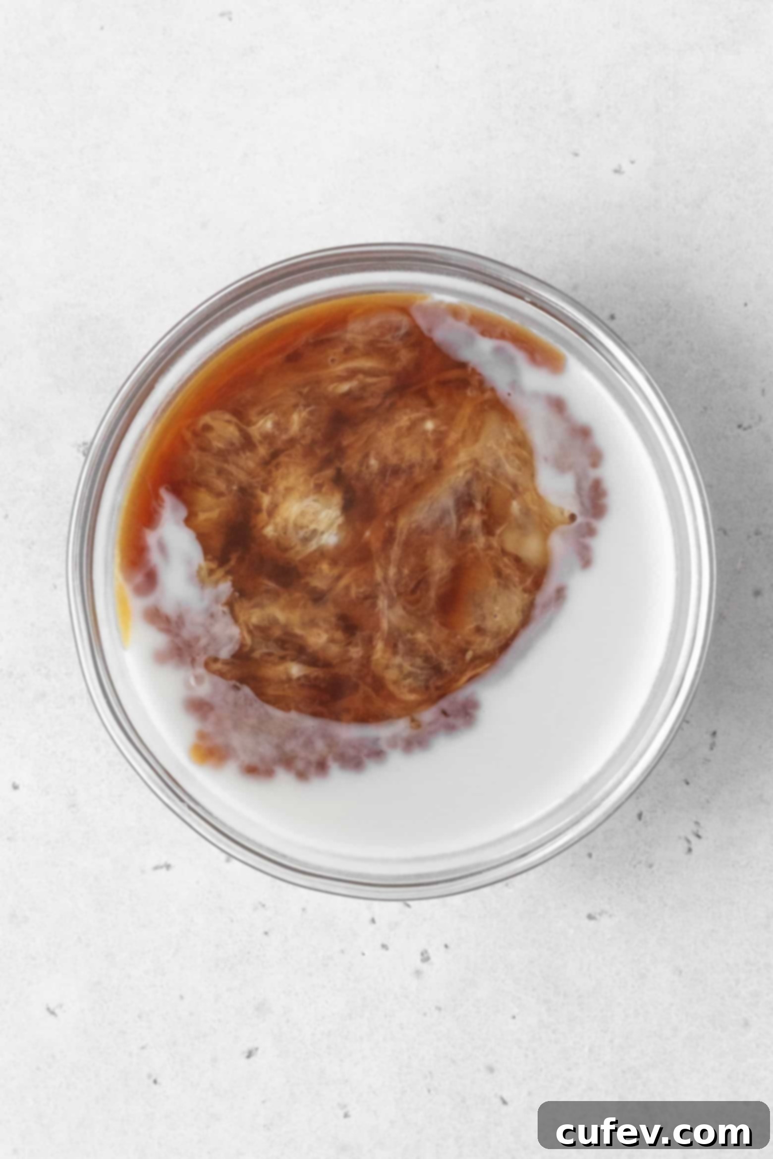 Adding vanilla extract and apple cider vinegar to milk in a small bowl.