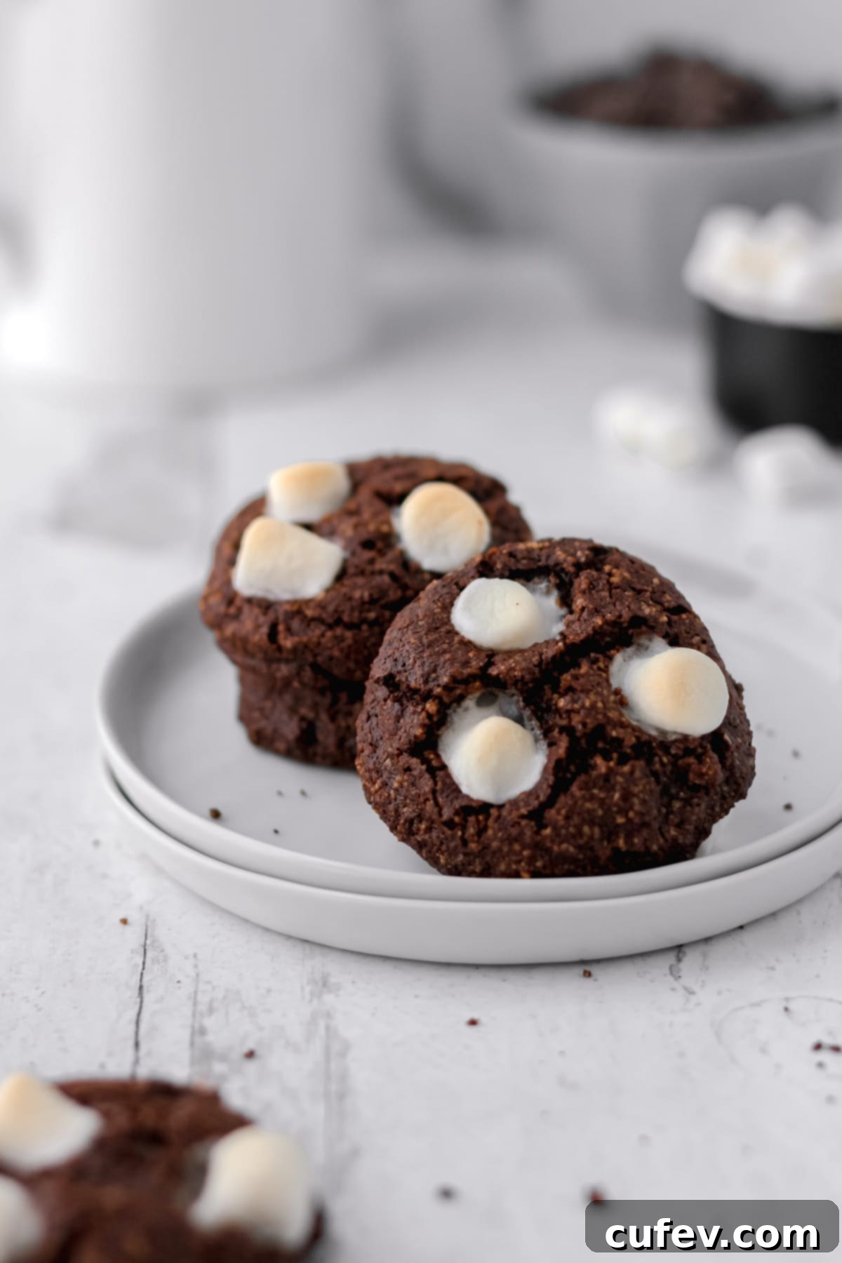 Hot cocoa cookies on a stack of small white plates.