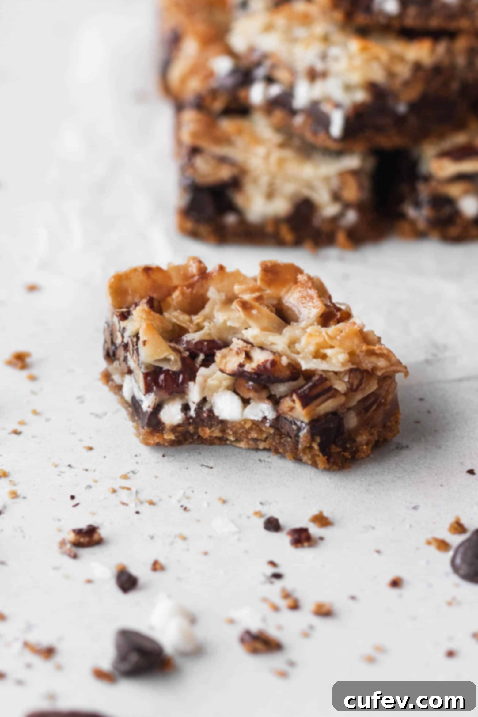 A close-up of a vegan 7 layer bar with a bite taken out, showing the gooey layers.