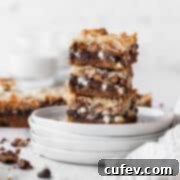 A stack of golden brown vegan magic bars on white plates, showcasing their distinct layers.