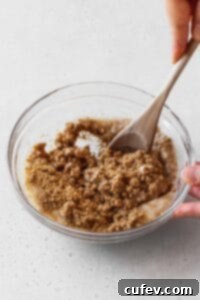 Mixing the graham cracker crumbs and butter with a wooden spoon.