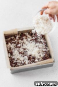 Sprinkling flaked coconut over the chopped pecans.