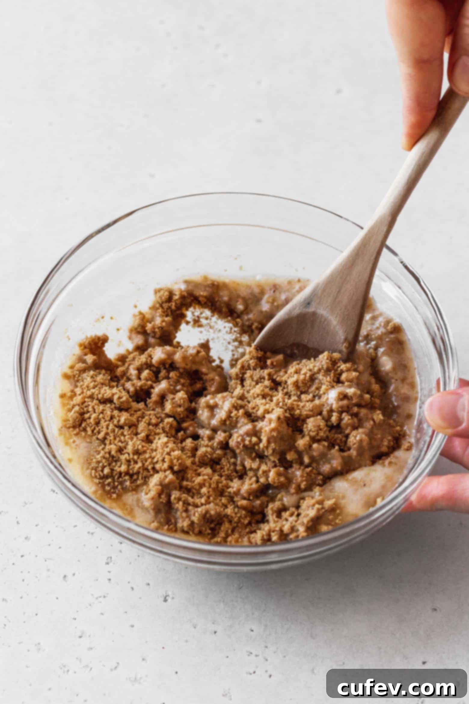 Mixing the graham cracker crumbs and melted vegan butter with a wooden spoon until well combined.
