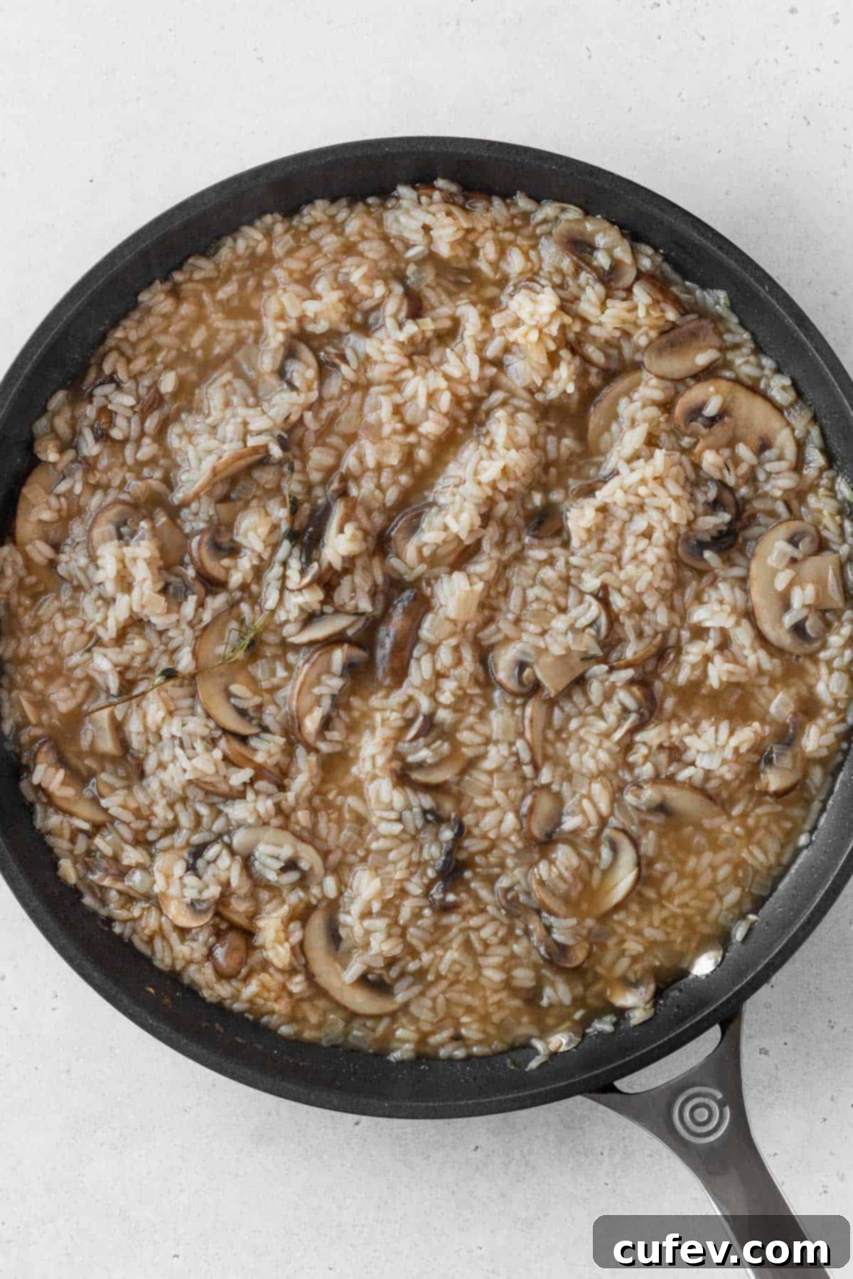 A large pan filled with fully cooked, creamy mushroom risotto, ready for the final additions.