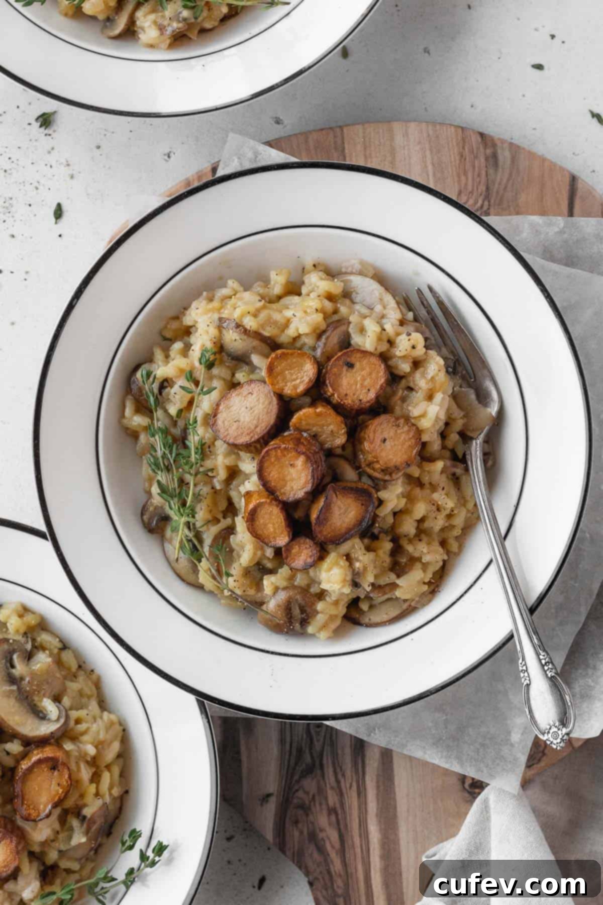 A white bowl of creamy vegan mushroom risotto with a silver fork resting on the side, ready to be enjoyed.