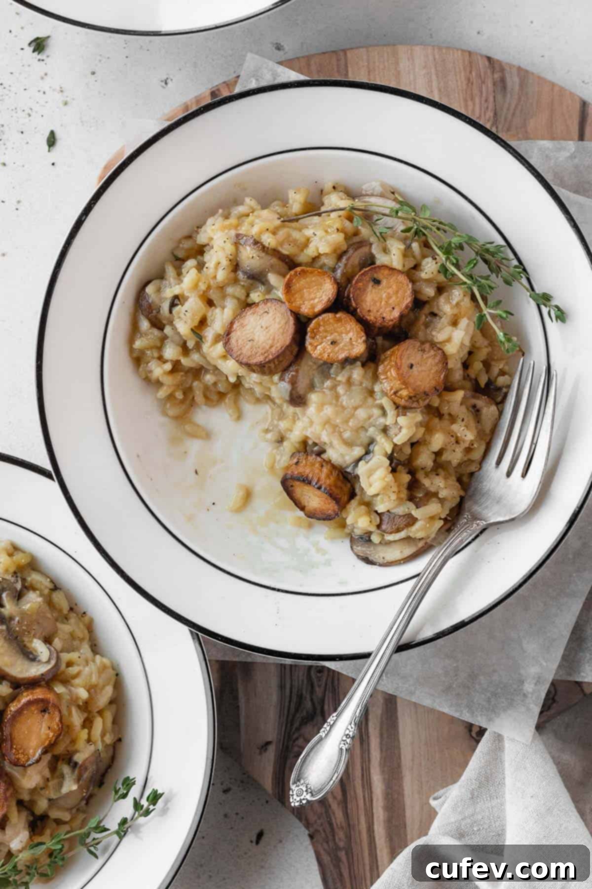 A partially eaten plate of creamy vegetarian risotto with pan-seared vegan scallops, showing the rich texture.