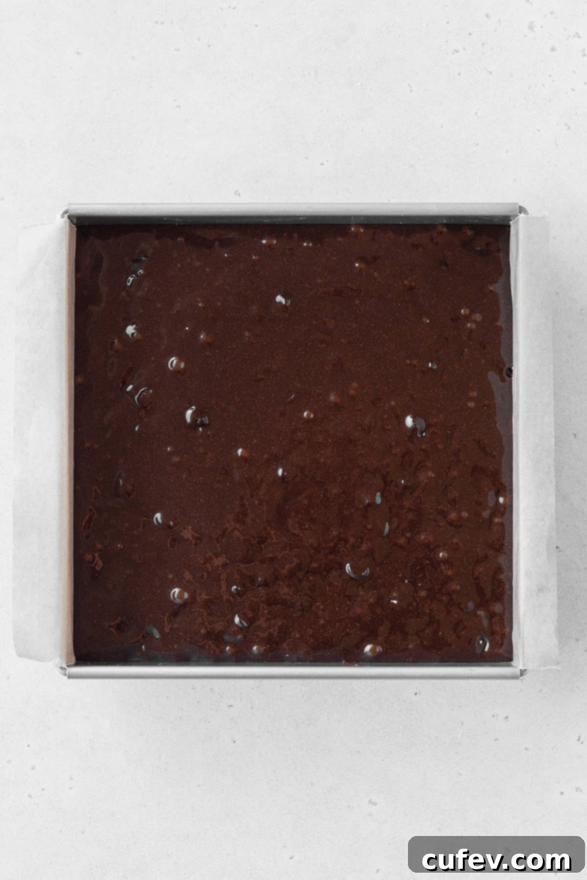 Gluten-free brownie batter poured into a square baking pan.