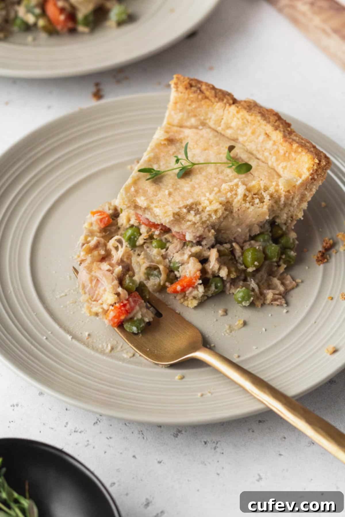 A perfectly baked slice of vegan chicken pot pie on a rustic plate, with a golden fork taking a delicious bite, showcasing the creamy filling and flaky crust.
