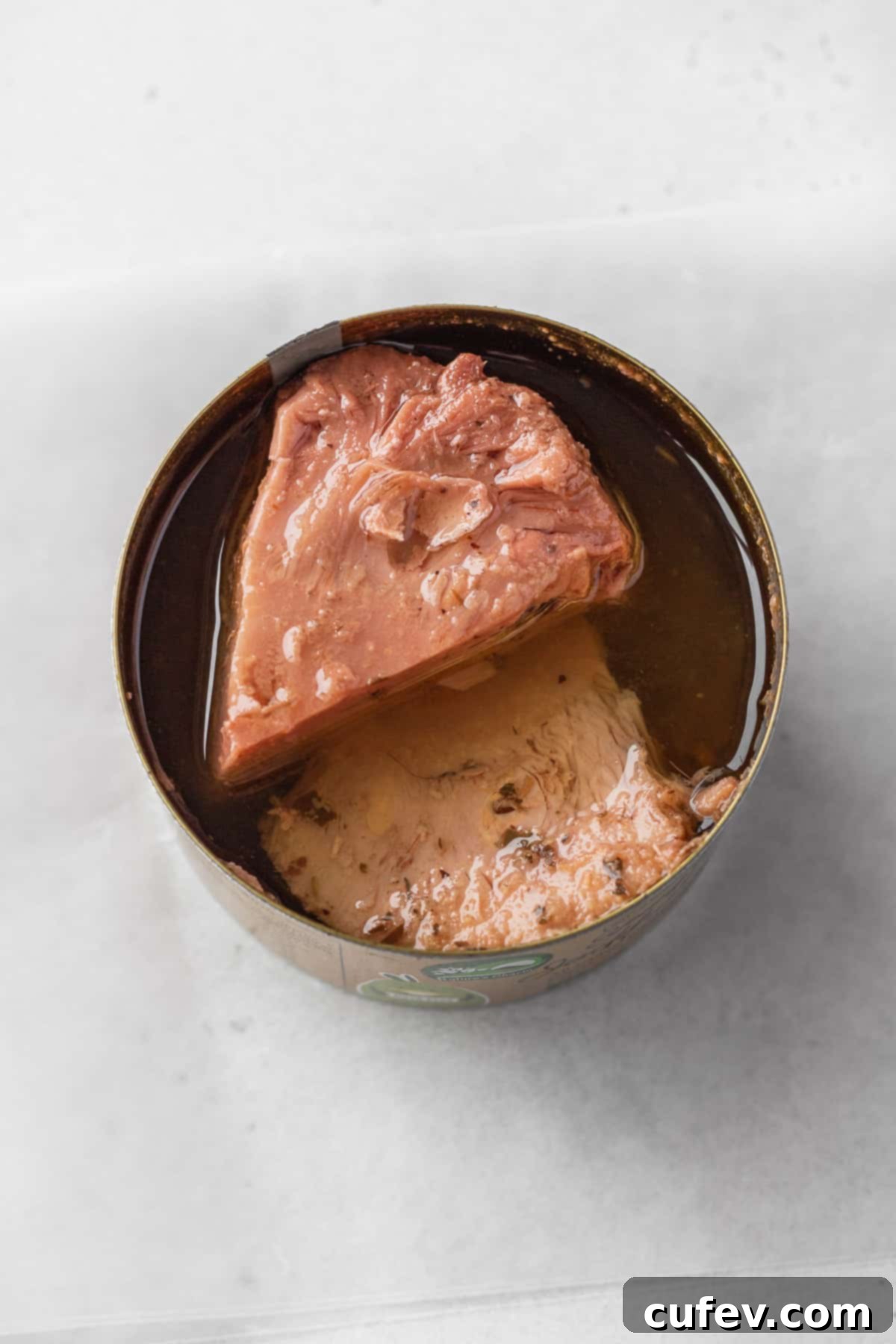 An opened can of Nature's Charm young green jackfruit confit, showing the tender, pre-seasoned jackfruit pieces in oil, ready for use.